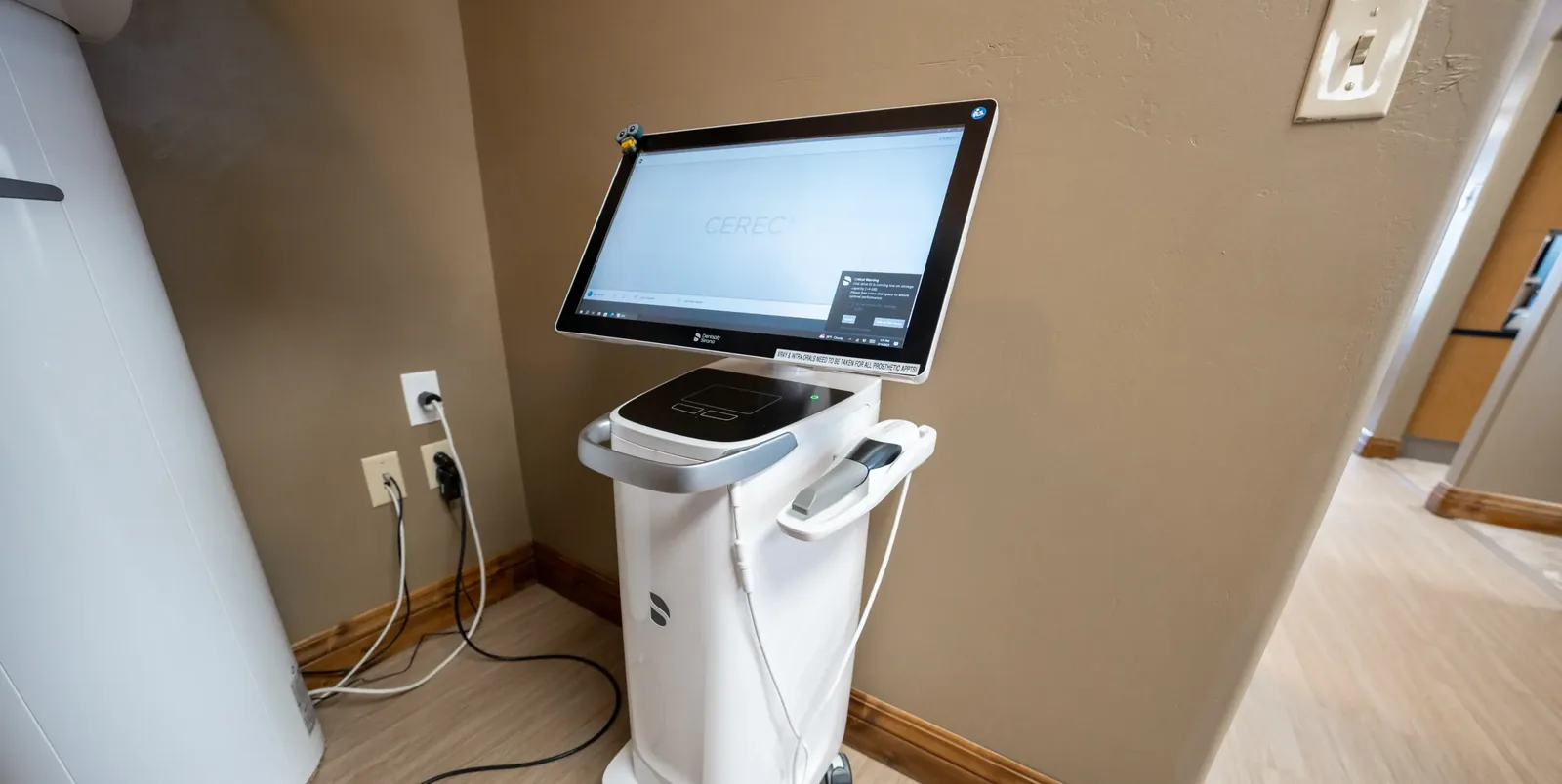 An intraoral scanner cart with a touchscreen monitor in a treatment room doorway.